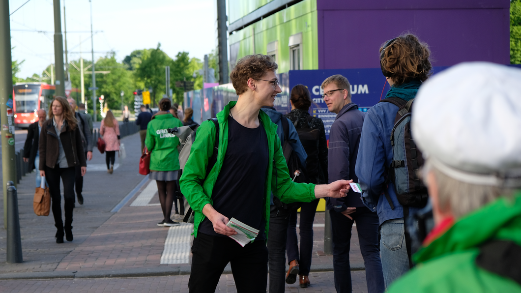 Een GroenLinks-vrijwilliger deelt flyers uit